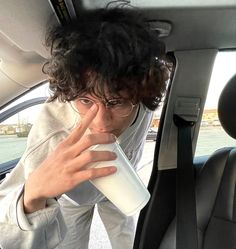 a man drinking from a cup while sitting in the back seat of a car,