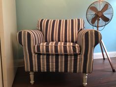 a striped chair with a fan in the corner