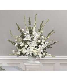 a vase filled with white flowers sitting on top of a table next to a wall