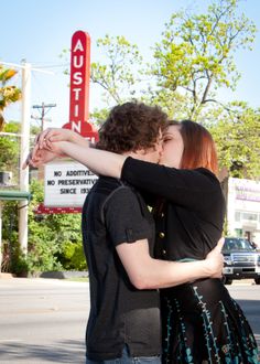 a man and woman kissing in front of a motel sign