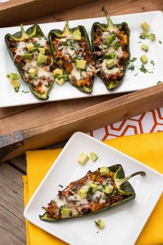 two plates filled with stuffed peppers on top of a yellow napkin next to a wooden tray