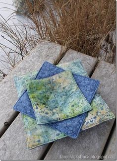 three blue and green coasters sitting on top of a wooden bench next to water