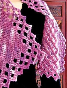 a pink crocheted shawl hanging from a door