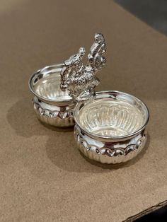 two silver dishes sitting on top of a table