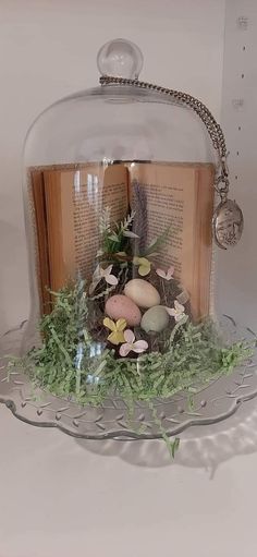 an open book under a glass dome with flowers and leaves on it's cover