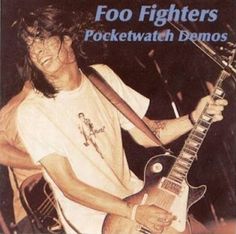 a man holding a guitar in his right hand and wearing a neck tie with the words foo fighters pocketwatch demos on it