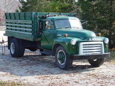 an old green truck is parked in the dirt