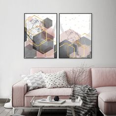 two paintings hanging on the wall above a pink couch and coffee table in a living room