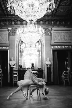 a woman sitting on top of a chair next to a chandelier in a room