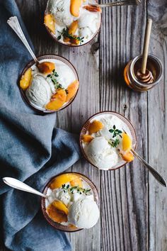 three small bowls filled with ice cream and peaches on top of a wooden table