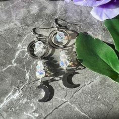 Shine bright like the goddess you are! These celestial moon earrings are sure to shine, and will give you a surprise with the sunlight.   Made with stainless steel and paired with a glass crystal bead, these earrings give a sparkle when the sun hits them, reminding you of a sun catcher! Light weight and perfect for every day wear or when you want to rock your celestial goddess side. Celestial Silver Pierced Crystal Earrings, Silver Celestial Crystal Earrings For Pierced Ears, Celestial Moon Charm Crystal Earrings, Silver Celestial Crystal Earrings, Nickel-free Celestial Crystal Earrings, Celestial Silver Crystal Earrings With Moon Charm, Silver Celestial Crystal Earrings With Moon Charm, Silver Moon-shaped Celestial Earrings, Silver Moon-shaped Celestial Crystal Earrings