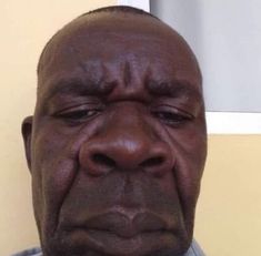 an older man with his eyes closed looking at the camera