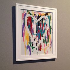 a painting is hanging on the wall next to a white framed art piece with paint splattered over it