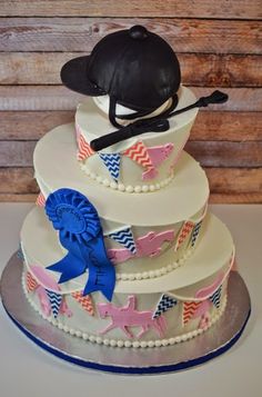 a three tiered cake with an equestrian theme on the top and blue ribbon around the edges