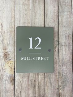 a metal sign that reads 12 mill street on it's side against a wooden wall