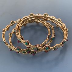 Very well ~ handmade ~ Vintage ~ gold plated ~ open-back faux gemstones stack-able bangle lot of 4 ~ Beautiful details all around . Unsigned from India Dates late 20th century . Materials : gold plated metal Faux gemstones enamel Measurements : Each bangle is approx 7 inches in wearable length x 1/4 inches max width ~ Inner diameter is 2 3/8 inches . Condition : Overall bracelet is in good vintage condition ~ No missing or replaced stone ~ some metal discoloration /darkening seen ~ Clasps are in Adjustable Jeweled Bangle Jewelry, Bohemian Hand Set Metal Bracelets, Bohemian Hand Set Bangle Bracelets, Festive Jeweled Metal Bracelets, Bohemian Hand Set Bangle Bracelet, Festive Metal Jeweled Bracelets, Metal Bangle With Jewels As A Gift, Stackable Metal Crystal Bangle Bracelet, Green Jeweled Bangle Bracelets