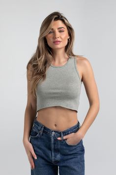 a woman wearing jeans and a cropped top with her hands on her hips, looking at the camera