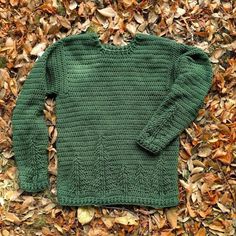 a green sweater is laying on the ground covered in leaves and fallen down to it's sides