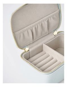 an open white leather jewelry case with gold trimmings on the bottom and inside