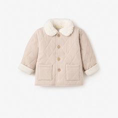 Our soft, cushiony quilted jacket is made from the softest materials and features a stylish, fuzzy vegan sherpa collar for extra warmth during those cold winter months. Pair with one of our coordinating cable knit baby hats or fun pom pom baby hats to complete the look.

Shell: 100% Organic Cotton, Collar: 100% Polyester Vegan Sherpa
Features quilted shell with wooden button closures
Machine wash warm, do not bleach, tumble dry normal, medium iron, do not dry clean Quilted Cream Puffer Jacket For Winter, Cream Quilted Puffer Jacket For Winter, Winter Cream Quilted Puffer Jacket, Cream Warm Outerwear For Cold Weather, Warm Cream Outerwear For Cold Weather, Winter Cotton Quilted Jacket For Cold Weather, Beige Cotton Cable Knit Outerwear, Winter Quilted Cotton Jacket For Cold Weather, Cream Quilted Long Sleeve Outerwear