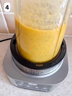 a blender filled with yellow liquid on top of a counter