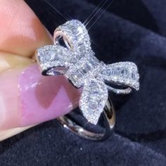 someone is holding a diamond ring in their left hand and it has a bow on the side