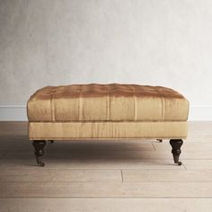 an ottoman sitting on top of a hard wood floor next to a white painted wall