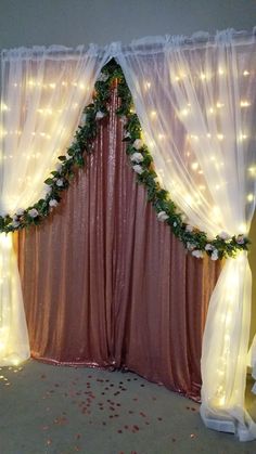 a decorated stage with lights and flowers on the curtained wall, along with rose petals