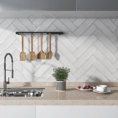 a kitchen with white tiles and wooden utensils hanging on the wall above the sink