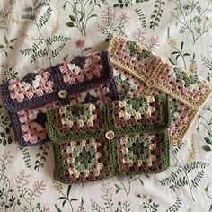 three crocheted purses sitting on top of a floral tablecloth covered bed