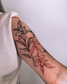 a woman's arm with flowers and leaves tattooed on the left side of her arm