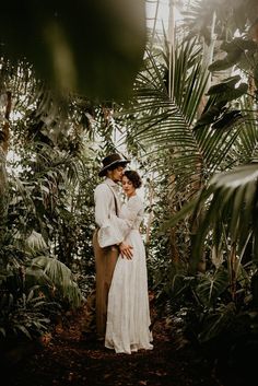 a man and woman standing next to each other in front of some palm trees on the ground