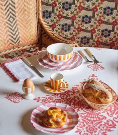 a table topped with plates and bowls filled with food next to a bowl of bread