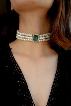 This stunner of a piece is an absolute show stealer. It features a green stone at the center and is lined with faux diamonds. The strings are strewn with shell pearls and accentuate the appeal of the centerpiece. Closure - Lobster. There's a subtle yet clearly indisputable quality in our traditional attires that brings out the depth of a woman's femininity. The warm glory of the gold, the ritualistic richness of red and green, the clamor of payals and kadas, are a celebration of womanhood. The m Luxury Diamond White Jeweled Diamond Jewelry, Elegant Jeweled Diamond White Jewelry, Elegant Diamond White Jeweled Jewelry, Elegant Crystal Jewelry With Gemstone Accents, Formal Jeweled Choker Jewelry, Elegant Jeweled Choker For Formal Occasions, Luxury Jeweled Diamond Jewelry, Formal Emerald Jewelry With Stones, Green Formal Jewelry With Stones