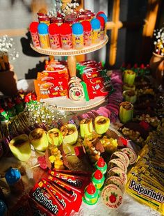 an assortment of candy and candies on a three tiered cake stand in front of other sweets