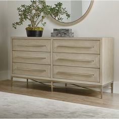 a wooden dresser sitting next to a mirror on top of a white rug in a room