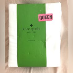 a green book sitting on top of a bed next to a white sheet and pink sticker