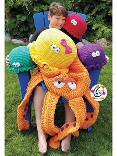 a young boy sitting in a chair with knitted octopus hats on his head and legs