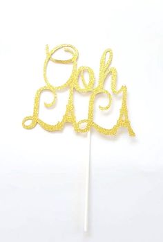 gold glitter cake topper with the word oh on it