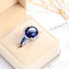 Brand New Ring Made Out Of 925 Sterling Silver With A 7/16" X 1/2" Large Oval Shaped Created Blue Sapphire Surrounded By Cubic Zirconias. The Ring Weighs 6 Grams. R0479-83 Cubic Zirconia Sapphire Ring, Blue Cubic Zirconia Crystal Ring, Royal Blue Round Jewelry With Center Stone, Formal Blue Crystal Ring With Halo Setting, Sapphire Jewelry With Lab-created Sapphire, Blue Crystal Ring With Cubic Zirconia, Blue Cubic Zirconia Crystal Ring For Anniversary, Formal Blue Sapphire Crystal Ring, Blue Round Lab-created Sapphire Jewelry