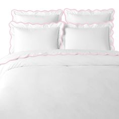 a white bed with pink scalloped trims and two pillows on top of it