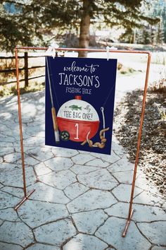 a sign that is on the side of a road in front of a fence and trees