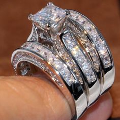 a close up of a person's hand holding two rings with diamonds on them