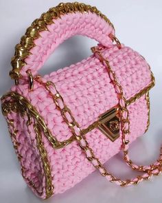 a pink crocheted purse with gold chains