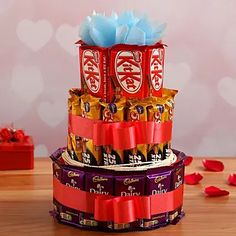 a stack of chocolate bars with blue ribbon and bow on top in front of valentine's day decorations