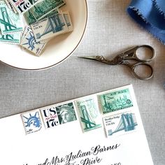 a pair of scissors sitting on top of a table next to a plate with stamps