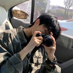 a man taking a photo in the back seat of a car with his camera up to his face