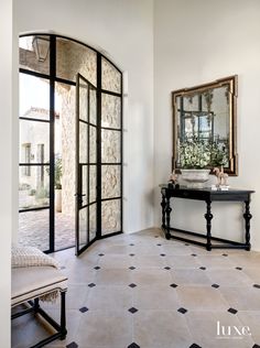 an entryway with a mirror, sink and bench in the center is decorated with black and white tiles