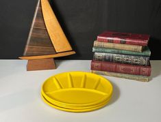 a stack of books sitting next to a yellow plate