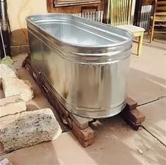 a large metal tub sitting on top of a wooden pallet next to a building